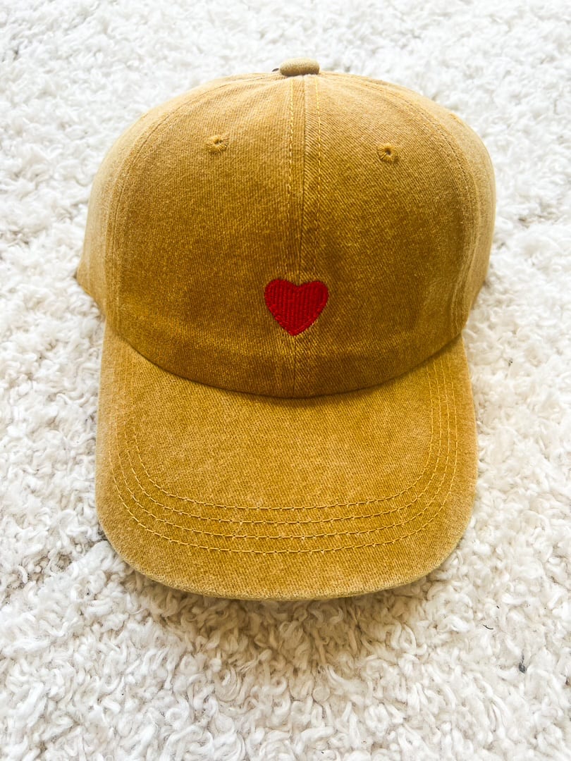 Casquette de couleur moutarde avec sa broderie coeur rouge